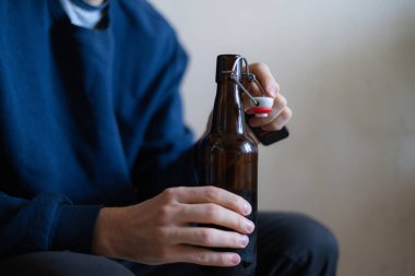 İçki şişesini elinde tutan adam depresyonda evde oturuyor, kötü alışkanlık sorunu.