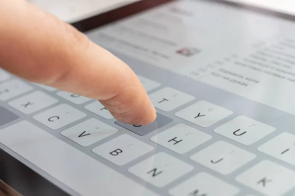 macro of a finger typing text on the touch screen keyboard of mobile device