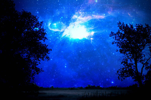 The stars in the sky above the wild nature field landscape. elements of this Image furnished by nasa