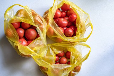 Plastik paketteki birçok kırmızı domatesin üst görüntüsü.