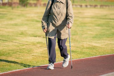 Yaşlı insanlar sabahları şehir yolunda yürüyor, sağlık için yavaş koşuyorlar.