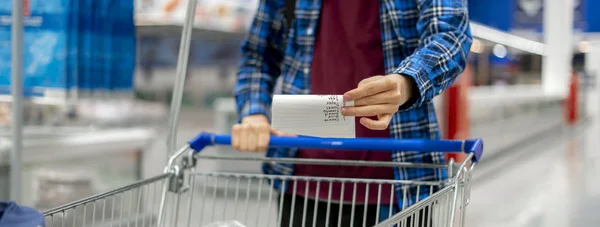 Руки человека, держащего лист со списком покупок и проверяющего покупку продуктов в продуктовом магазине — стоковое фото