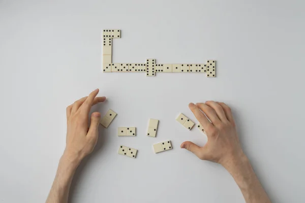 Una mano cercana de la persona sosteniendo piezas dominó y jugar el juego en la mesa blanca — Foto de Stock