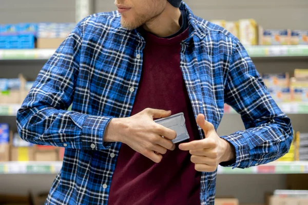 Cleptomanía concepto, un hombre en la tienda de comestibles robar comida y ponerlo en el bolsillo — Foto de Stock