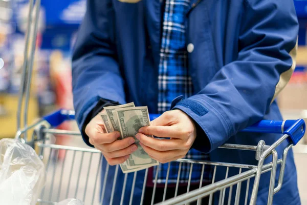 a person in a grocery store, hands count the money currency