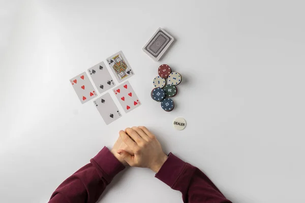 Лучший вид дилера, держащего фишки и карты в игре в покер на белом столе — стоковое фото