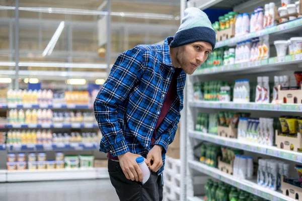 Kleptomania concept, a man in the grocery store stealing food and put it in the pocket — Stock Photo, Image