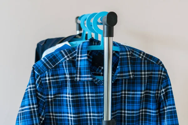Simple wardrobe hanger of casual clothes at home, simple isolated against the wall — 图库照片