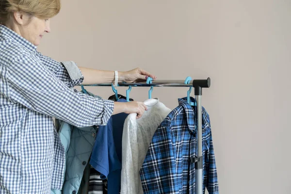 The woman searching the clothes on the hanger at home and pick the right one — Stok fotoğraf