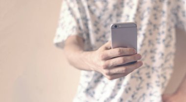 Akıllı telefon kullanarak duvarın yanında dikilen sıradan bir hippi. Sosyal sorunlar, sosyal kişisel sorunlar