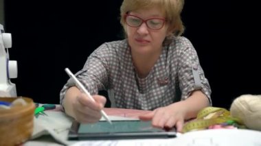 female clothes designer draw sketches on digital tablet in the studio at the tables