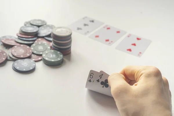 close up poker player holding a playing card on the table, win or loose simple concept