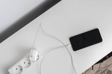 Telefon kablosu olan bir soket beyaz rafta hızlı şarj aleti.