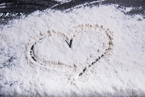 Coeur peint avec le doigt dans la farine de blé sur une surface de travail grise — Photo