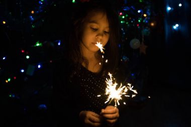 Küçük kız bir Noel ağacı arka plan üzerinde bir maytap ateş etmeyin