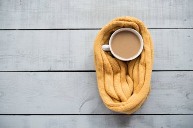Kahve kupa, bisküvi, çiçek yaprakları, ahşap bir masa üzerinde sarı atkı örgü