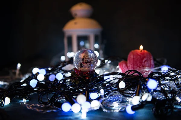 Uma vela vermelha com luzes de Natal na luz atmosférica — Fotografia de Stock