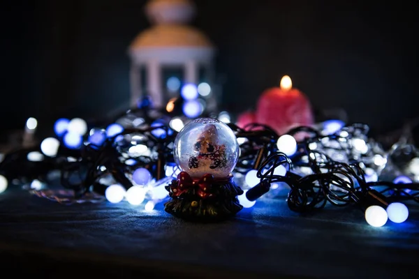 Uma vela vermelha com luzes de Natal na luz atmosférica — Fotografia de Stock