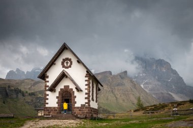 Sarı yağmurluk Rolle Pass, Ital chapel infront kadında