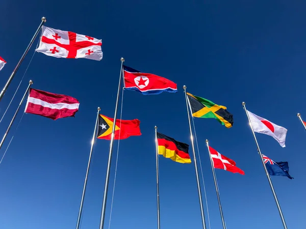 Vlajky několika zemí mávat před modrá obloha — Stock fotografie
