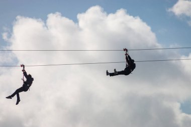İnsanlar teleferik hattı kullanarak eğleniyor.
