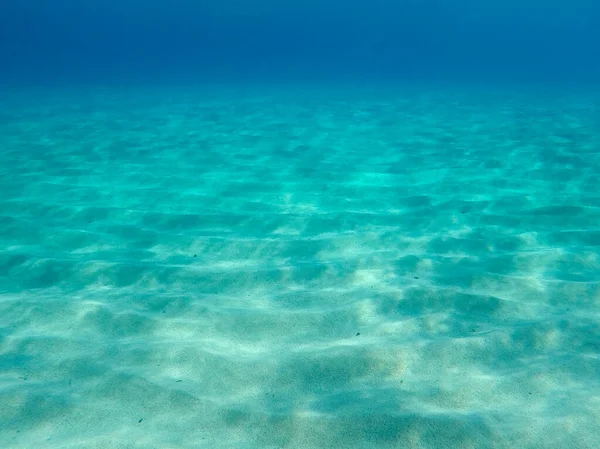 Sandy underwater sand on a shallow seabed in the Mediterranean sea with reflections of sunlight, natural scene, Sardinia, Italy