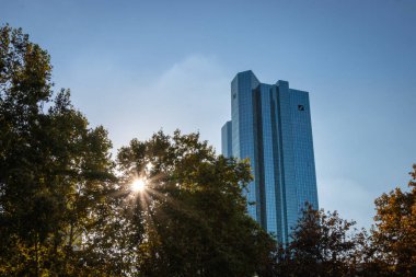 Frankfurt am Main, Almanya - 21 Ekim 2018: Deutsche Bank 'ın İkiz Kuleleri Sonbahar mevsiminde yeşillik ağaçlarla kaplı güneşe karşı