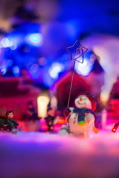 Boneco de neve detém estrela de belém fica na frente da miniatura vil — Fotografia de Stock