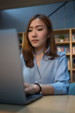 Dizüstü bilgisayarda kütüphanede çalışan Asya iş kadın.