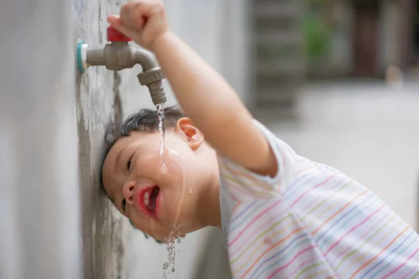 Дети пьют водопроводную воду . Лицензионные Стоковые Фото