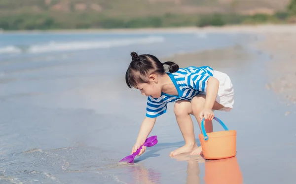 Pouco asiático bebê menina jogando areia na praia. Miúdo três anos — Fotografia de Stock