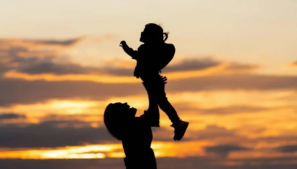 Silhouette of asian mother and daughter in sunset sky. — Stock Photo, Image