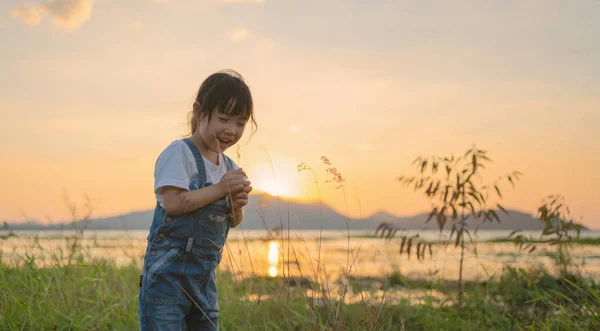 Little asian girl have happiness and enjoy in a green field with — Stock Photo, Image