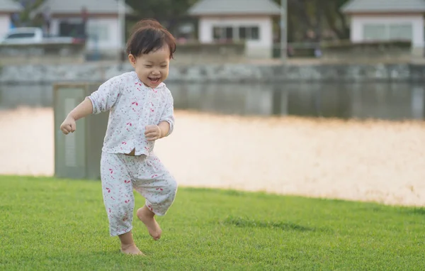 Asian little girl playing on the lawn happy and enjoy in the par — Stock Photo, Image