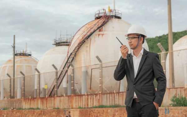 Engineer holding radio communications to control work within the oil refinery. Energy and petrochemical industry. Engineer Concept.
