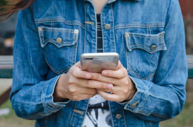 Kız akıllı phonea kullanarak kot ceketli