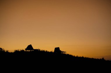 Tayland 'da günbatımına karşı bir tepedeki kulübelerin silueti