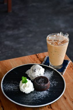 Ahşap masada çikolatalı lava kekiyle buzlu kahve.