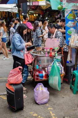 CHATUCHAK, BANGKOK, THAILAND, NOV 19, 2017: Chatuchak Haftasonu Pazarı 'nda Tay dondurması alan turist, Kasım 2017