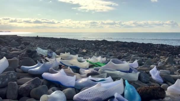 Забруднений берег, сміття на пляжі, порожні пластикові пляшки, гумове взуття — стокове відео