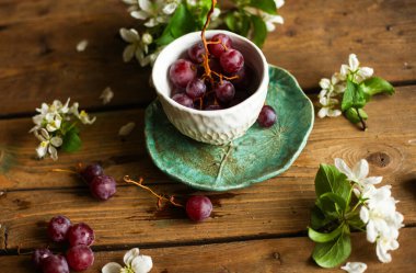 bahar durgunluğu, üzümlü bir bardak ve masanın üzerinde çiçek açan elma ağacı dalı..