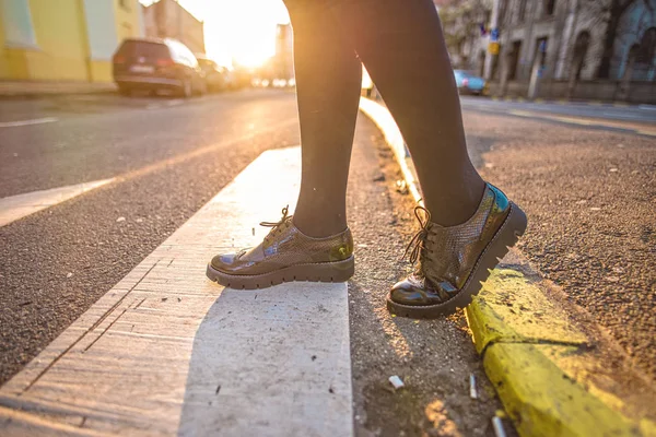 Trendy and classic woman shoes on street. Close-up of female legs with leather shoes