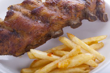 patates kızartması ile beyaz bir tabak içinde sulu Barbekü Domuz kaburga ızgara.