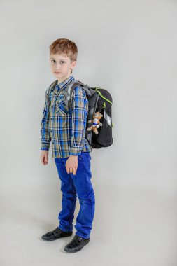 Sevimli Kafkas çocuğun portresi, gri arka planda izole sırt çantası ile ilköğretim öğrencisi. çocuk yaşı 7 yaş ilk sınıf öğrencisi tam uzunlukta görünüm.