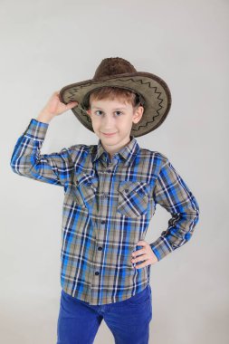 Sevimli beyaz çocuk, gri arka plan üzerinde kovboy şapkalı ilköğretim okulu öğrenci portresi. 7 yıl birinci sınıf öğrencisi çocuk yaşlı.