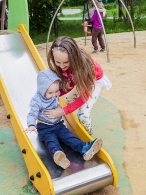 kız ve erkek kardeş Playgrou üzerinde oynama. Kız çocuk slayt üzerinde küçük bir çocuk yardımcı olur. çocukların güvenliğine yürüyüşte kavramı. genç kız kendine iyi bak küçük çocuklar.