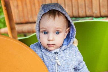 Şirin yürümeye başlayan çocuk bahçesi kum havuzunda bahar güneşli bir günde oynamaya. Akıllı neşeli çocuk bir yürüyüş. bir çocuğun oyuncak evde yakın çekim portre.