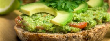 Avokado, domates, limon, poarsley ve sarımsaktan yapılmış guacamole ile bir dilim ekmek.