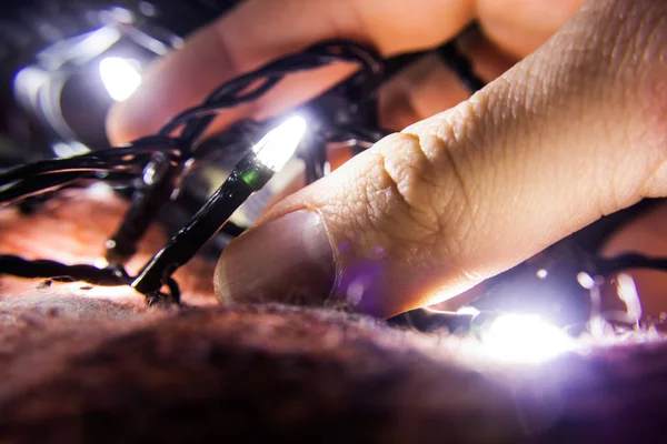 Hombre mano agarrando año nuevo luces en coveret —  Fotos de Stock