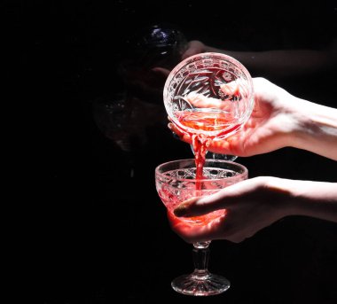 İki el, arka planda şarap bardakları tutuyor.